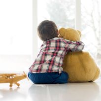Little child sitting in living room with teddy bear